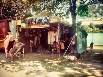 virblatt Verkaufsstand für Festival Kleidung mit Haremshosen und alternativer Hippie-Bekleidung am Seeufer, mit Schaufensterpuppe und Verkäufer im Boho-Look